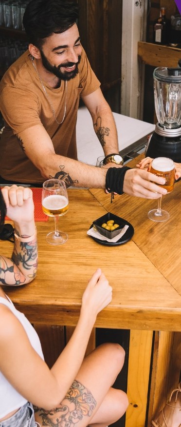 Two customers with drinks at a wooden bar counter